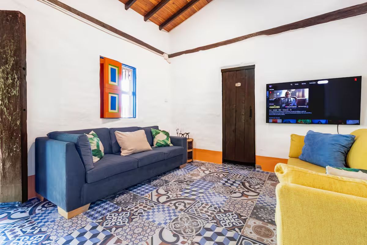 The living room — patchwork tile, blue couch, yellow chair